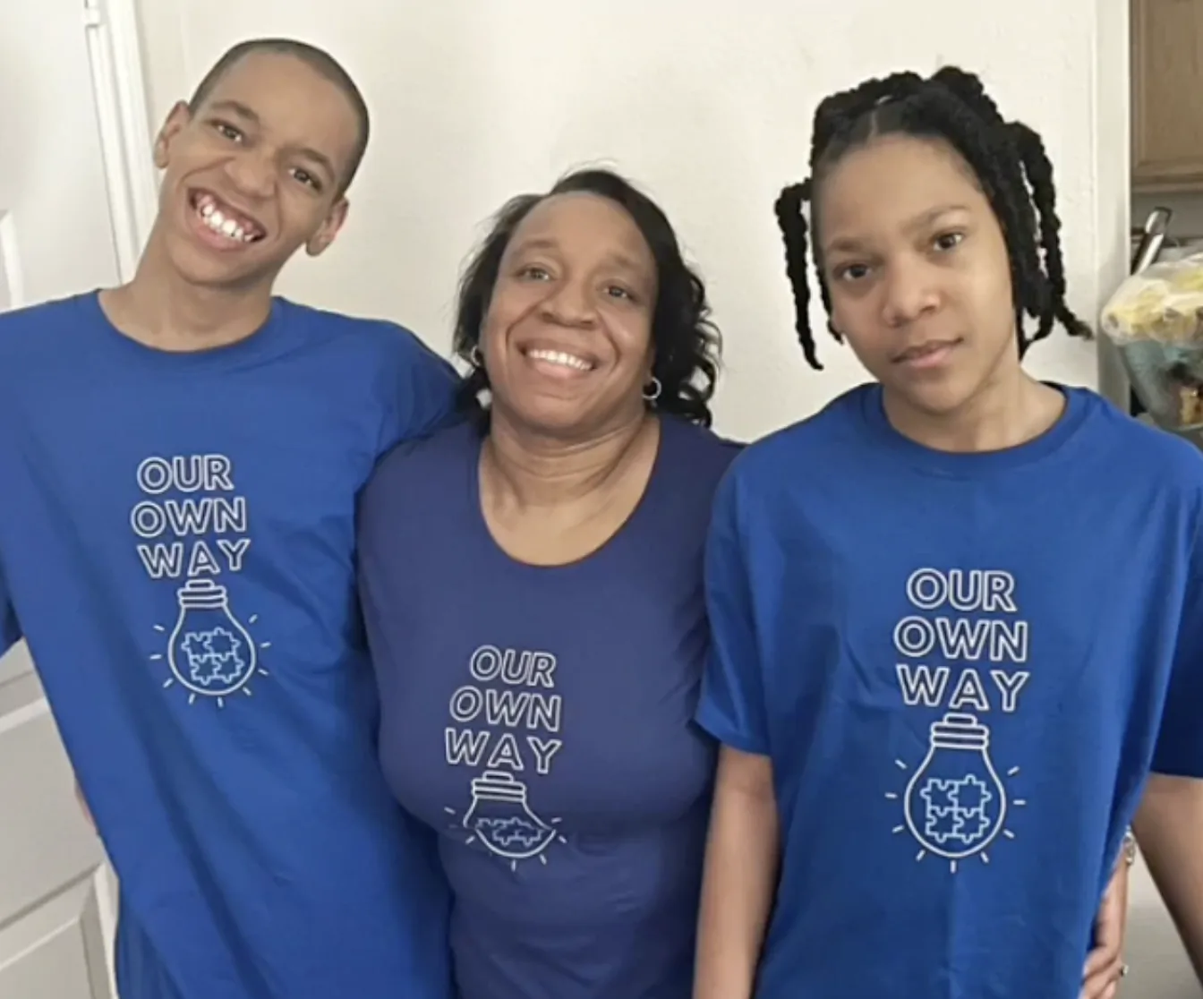 Store owner with her two autistic sons in matching Our Own Way shirts.